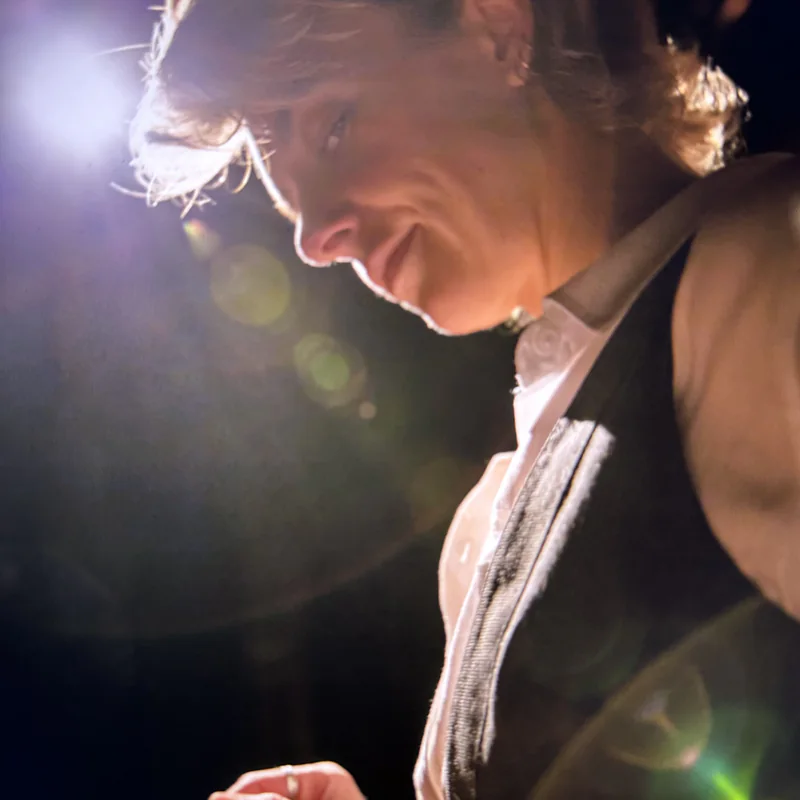 Ellie J smiling down mid-performance under a bright stage light